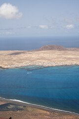 Wall Mural - Views of the island of La Graciosa from the viewpoint of El Rio. Turquoise ocean. Blue sky with big white clouds. Caleta de Sebo. Town. volcanoes. Lanzarote, Canary Islands, Spain