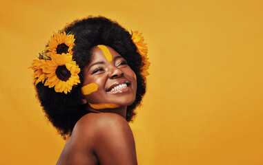 Beautiful black woman, sunflowers in hair and make up on face in studio for cosmetics, afro care and empowerment. Happy, lady and mustard paint on forehead for summer, spring or warmer weather