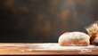 A loaf of bread sits on a wooden table with a bowl of flour next to it