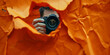 Photographer Capturing Shot Through Orange Torn Paper Backdrop