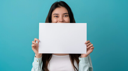 Wall Mural - smiling young woman holding mockup white paper on blue background with copy space