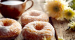 A close-up of a plate of donuts, lightly dusted with sugar, sits on an old wooden table next to a cup of tea