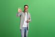 Portrait of satisfied handsome customer smiling and showing OK sign on isolated green background