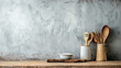 Wooden utensils and ceramic bowls arranged neatly on a rustic wooden countertop against a textured grey wall
