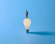 Individual atop a lightbulb, innovative thinking, blue sky thinking, minimalist , clean sharp focus