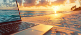 Fototapeta  - close-up open laptop notebook computer lying on the beach sand at golden sunset light with crashing beach waves created with Generative AI Technology
