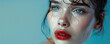 Portrait of a young sad crying woman with smeared red lipstick and flowing mascara on blue colored background with copy space.