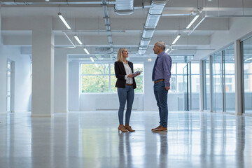 A female real estate agent shows an empty office space to a potential buyer or tenant.
