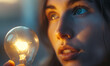 Close up calm young woman or girl looking holding a light bulb in her hand thinking of invention of sustainable and less consumptive energy source