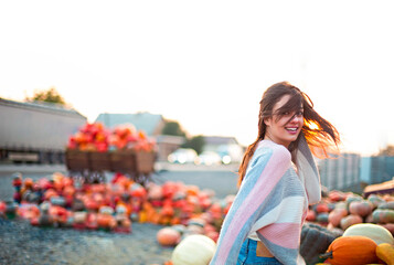 Fashionable beautiful young girl at the autumn pumpkin patch background. Having fun and posing