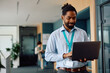 © Drazen - Smiling black businessman using laptop while working in office.
