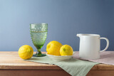 Fototapeta Nowy Jork - Summer composition with lemons and white jug on kitchen wooden table