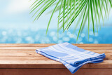 Fototapeta  - Empty wooden table with blue tablecloth over tropical beach bokeh background.  Summer mock up for design and product display.