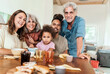 © Lomb - Portrait of a happy multigenerational family posing at breakfast table indoors at home.