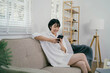 A woman is sitting on a couch and looking at her cell phone