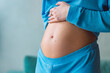 Close-up of young pregnant woman touching her belly and caring about her health. Motherhood and baby expectation concept