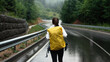 Attractive young woman with backpack walking alone among rainy mountains. Outdoors activity during free time. Concept of hiking, people and nature.