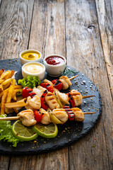 Wall Mural - Meat skewers - grilled meat with French fries and fresh  vegetables on wooden background
