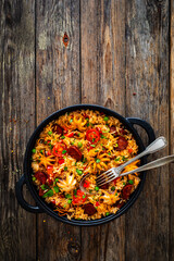 Wall Mural - Paella seafood and chorizo in cooking pan on wooden table
