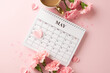 Celebrating mother's day: flat lay of may calendar with carnations and coffee on a pink background