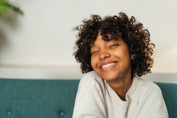 Beautiful African American girl with afro hairstyle smiling. Close up portrait of young happy black girl. Young African woman with curly hair laughing. Freedom happiness carefree happy people concept