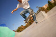 Close up of active young man riding skateboard in skate park on sunny day. Extreme sport concept