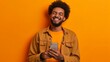 Isolated young man using mobile smart phone on a orange background - Millennial holding cellphone - People and technology concept