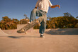 Close up of young man riding skateboard in skate park on sunny day. Extreme sport concept