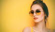 Attractive woman wearing sunglasses closeup. Woman clad in stylish trendy outfit and looks contemplatively at camera with slight smile on face