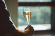 A photo of a hand holding a glass of champagne with bubbles on sunset light. Celebration or holiday concept.