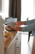 Close-up. Hands reach for a cup against the background of a home interior. Vertical frame.