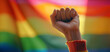 A woman protests with her fist raised on gay pride day with the LGBT flag in the background