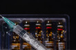 A Syringe and Medicine Ampoules out of focus on the Background