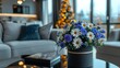   A blue and white flower bouquet rests on a table, facing a couch Behind the scene, a Christmas tree stands in the background