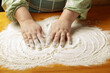 Women's hands spread a thin layer of flour on the table