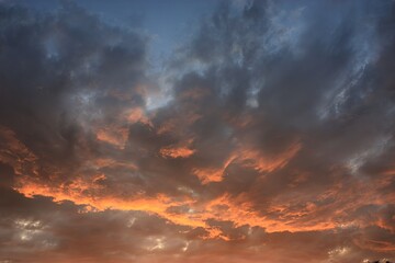 Dramatic sunset sky with vibrant orange, red and yellow colors, illuminated by the setting suns warm light, creating a stunning natural display of beauty and tranquility