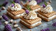   A table, laden with mini waffles, is topped with frosting and generously decorated with whipped cream Lavender sprigs gracefully adorn the top