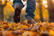 A cute father and baby's adorable little shoes stepping on fallen autumn leaves in a park.