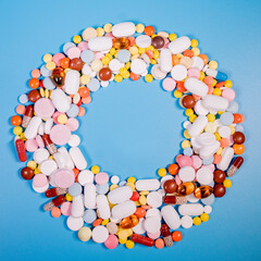 Wall Mural - Frame with colorful pills and capsules on a blue background. Place for text