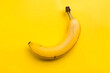 Perched atop a vibrant yellow backdrop, a perfectly ripe banana beckons with its fresh allure, promising a burst of sweetness and energy
