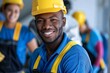 A joyful male construction worker in a yellow helmet is surrounded by colleagues in a work environment
