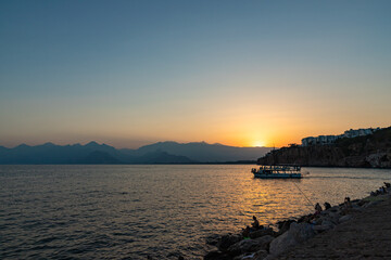 Wall Mural - ANTALYA, TURKYE - SEPTEMBER 17, 2022: Old harbour in Antalya at sunset with tourists boat at front