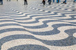 People Walking on Undulating, Dizzying Waves of Black and White Limestone Tiles on a Sidewalk in Lisbon, Portugal