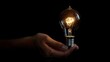 © Matcha_09 - Lit lightbulb held in hand on black background
