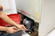 man's hands repairing refrigerator at home.