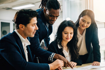 Wall Mural - In a meeting room, a global team engages in lively discussion, led by a female leader. Together, they plan and collaborate on strategies, analyze charts, and work with documents for success.