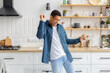 Happy African American man dancing listening to music at home kitchen