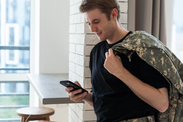 Young army man using smartphone at home