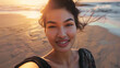 © Cavan Images - Asian young woman smiling taking selfie on the beach,