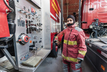 Female Firefighter In Fire Protection Suit Standing At Fire Station